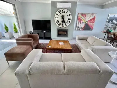 a living room with a couch and a clock on the wall at Franschhoek Gem on Van Wijk in Franschhoek