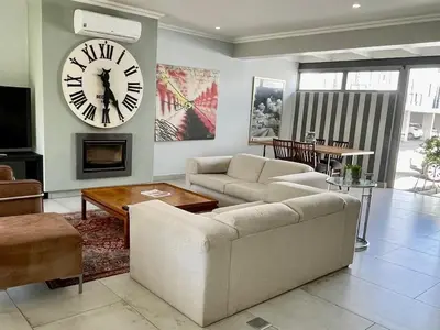 a living room with a couch and a clock on the wall at Franschhoek Gem on Van Wijk in Franschhoek
