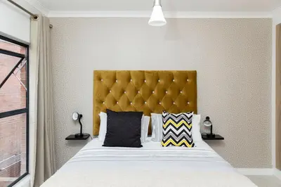 a bedroom with a large bed with a yellow headboard at #AlimamaSpaces Manson's Fynbos Villa in Cape Town