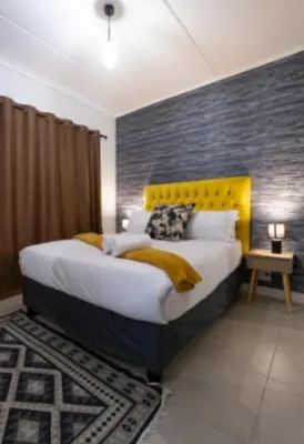a bedroom with a large bed with a yellow headboard at #AlimamaSpaces Manson's Fynbos Villa in Cape Town