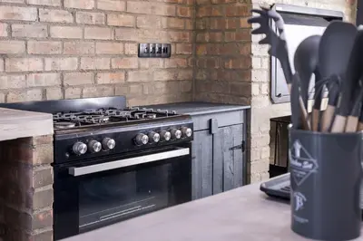 a kitchen with a black stove and a brick wall at My Venue at Avemore in Onder-Papegaaiberg