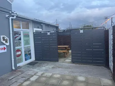 an open gate to a patio with a wooden table at Cozy Corner Guest House 25 Harpford avenue wynberg CAPE TOWN WESTERN CAPE in Cape Town