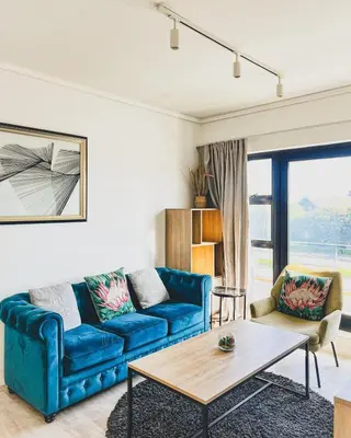 a living room with a blue couch and a table at Shiloh Apartment on Burmeister in Cape Town