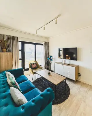 a living room with a blue couch and a table at Shiloh Apartment on Burmeister in Cape Town