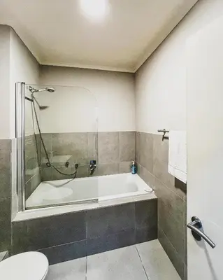 a bathroom with a bath tub and a toilet at Spacious 2 bedroom Apt near Canal Walk in Cape Town