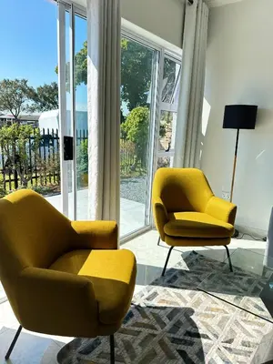 two yellow chairs in a living room with windows at Lux Sleek City Haven in Cape Town