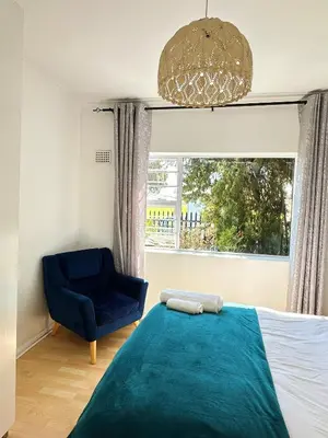 a bedroom with a bed and a chair and a window at Lux Sleek City Haven in Cape Town