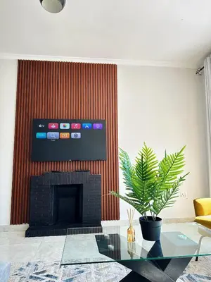 a living room with a fireplace and a tv on a wall at Lux Sleek City Haven in Cape Town