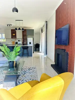a living room with a fireplace and a tv on a wall at Lux Sleek City Haven in Cape Town
