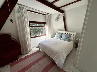 a bedroom with a white bed and a window at Protea Escape - sea, sand and sun on your doorstep in Hermanus
