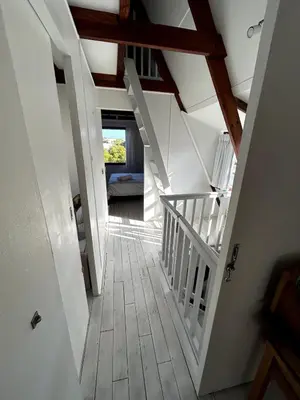 an attic hallway with white stairs and a window at Protea Escape - sea, sand and sun on your doorstep in Hermanus