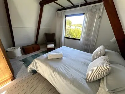 a bedroom with a large bed with a window at Protea Escape - sea, sand and sun on your doorstep in Hermanus