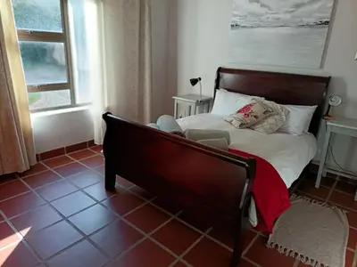 a bedroom with a bed with white sheets and a window at Beautifully Sea View Escape Vermont 5 bedrooms in Hermanus