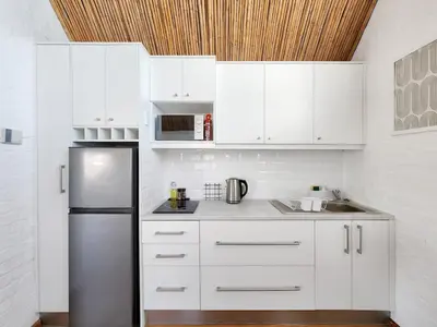 a kitchen with white cabinets and a stainless steel refrigerator at The Nest at Durbanville in Cape Town
