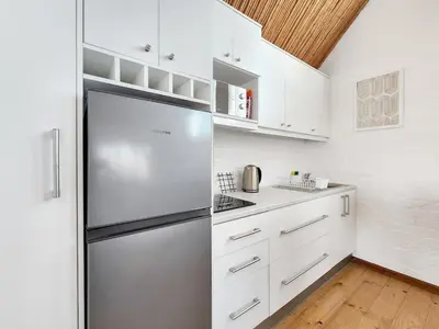 a kitchen with white cabinets and a stainless steel refrigerator at The Nest at Durbanville in Cape Town