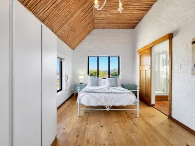 a bedroom with a bed with white sheets and wood ceilings at The Nest at Durbanville in Cape Town