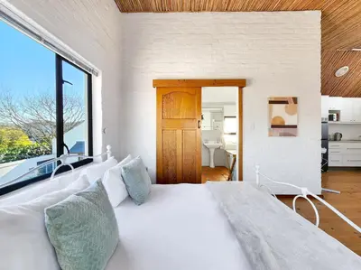 a white bed in a room with a large window at The Nest at Durbanville in Cape Town