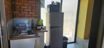 a small kitchen with a refrigerator next to a brick wall at LyonsDen 1 in Worcester