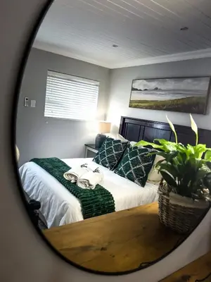 a bedroom with a bed with a table and a mirror at Ziminé Cottage in Paarl