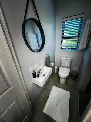 a bathroom with a white toilet and a mirror at Ziminé Cottage in Paarl