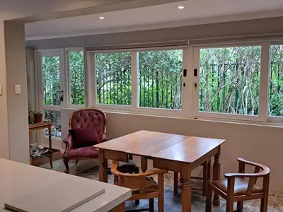 a room with a table and chairs and windows at Spacious Sunny family home in secure leafy sought after area in Stellenbosch
