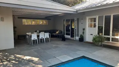 a patio with a table and chairs and a pool at Spacious Sunny family home in secure leafy sought after area in Stellenbosch