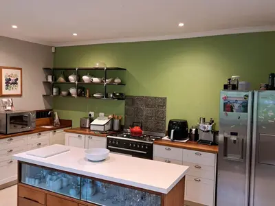 a kitchen with white cabinets and a green wall at Spacious Sunny family home in secure leafy sought after area in Stellenbosch