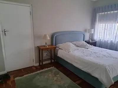 a bedroom with a bed with a blue headboard and a window at Spacious Sunny family home in secure leafy sought after area in Stellenbosch