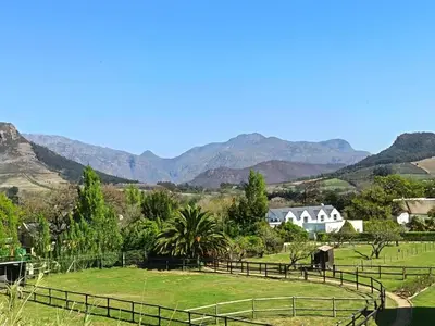 a view of a farm with mountains in the background at La Jolie Dauphine Guest House in Franschhoek