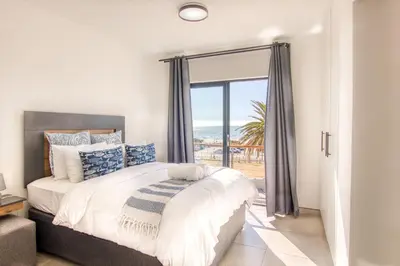 a bedroom with a bed with a view of the ocean at Ocean & Mountain View Escape, 100m Walk to beach - Gordon's Bay in Gordonʼs Bay
