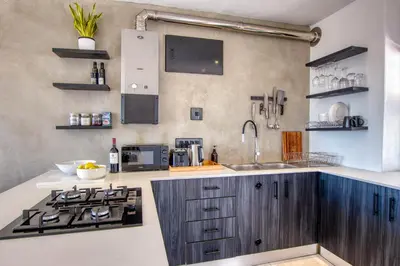 a kitchen with a sink and a stove at Ocean & Mountain View Escape, 100m Walk to beach - Gordon's Bay in Gordonʼs Bay