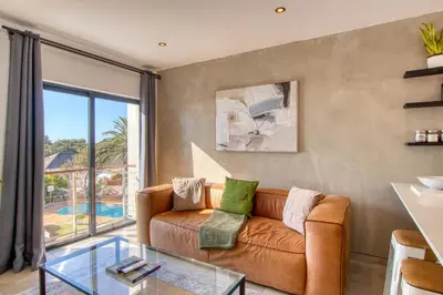 a living room with a couch and a glass table at Ocean & Mountain View Escape, 100m Walk to beach - Gordon's Bay in Gordonʼs Bay