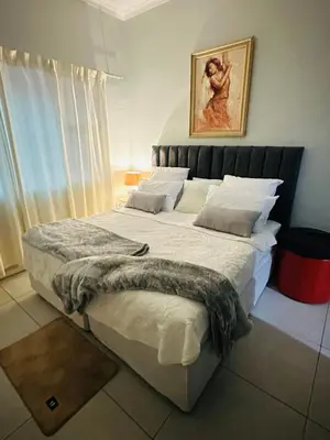 a bedroom with a large bed with white sheets at AAA Luxury Homes in Cape Town
