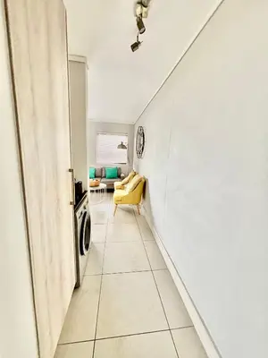a hallway with a yellow chair in a room at Luxe Waters Edge apt next to Canal Walk in Cape Town