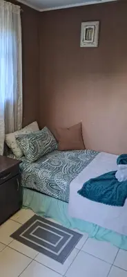 a bed with a comforter and pillows on it at Clay Stone Cottage in Goodwood