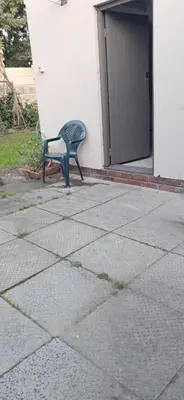 a green chair sitting in front of a building at Clay Stone Cottage in Goodwood
