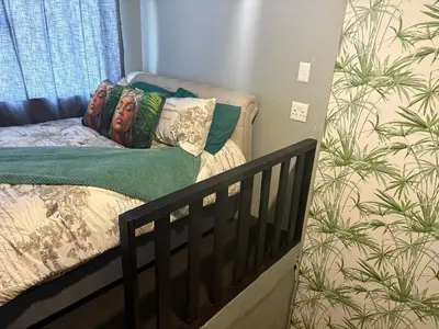 a crib in a room with a bed with pillows at TLP Haven in Cape Town