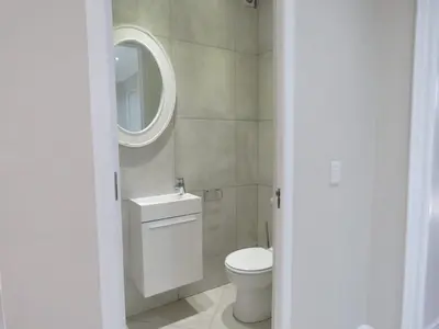 a bathroom with a white toilet and a mirror at Penthouse on the beach, Jacuzzi with 3 bedrooms in Cape Town