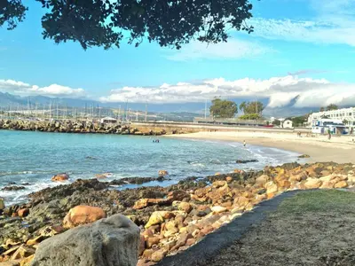 a beach with rocks and people in the water at Penthouse on the beach, Jacuzzi with 3 bedrooms in Cape Town