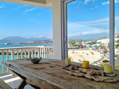 a table on a balcony with a view of a beach at Penthouse on the beach, Jacuzzi with 3 bedrooms in Cape Town