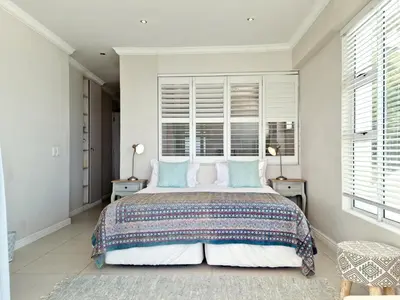 a bedroom with a large bed with blue pillows at Penthouse on the beach, Jacuzzi with 3 bedrooms in Cape Town