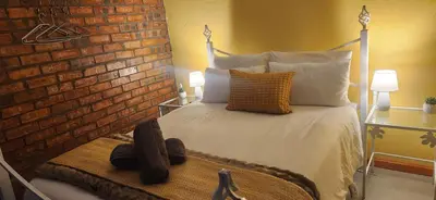 a bedroom with a white bed with a brick wall at LyonsDen 2 in Worcester