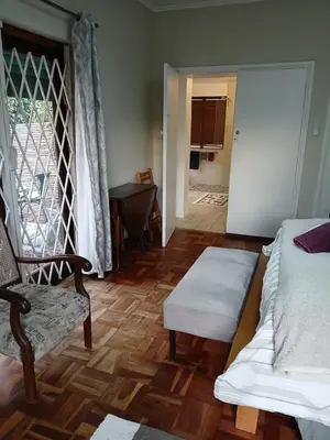 a room with a bed and a chair and a door at Rusticana A in Cape Town