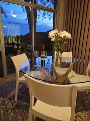 a glass table with a bottle of wine and two chairs at Max 7 in Helderberg