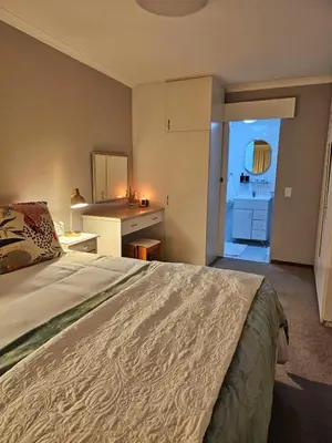 a bedroom with a large bed and a kitchen at Max 7 in Helderberg