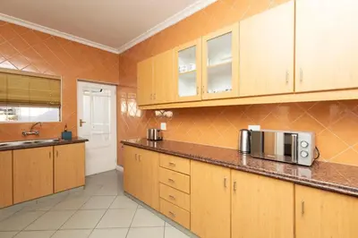 a kitchen with wooden cabinets and a microwave at Serena Inn Apartment 6 Self Catering in Cape Town