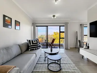 a living room with a couch and a table at Rivers Edge Apartment in Rondebosch with Balcony in Cape Town
