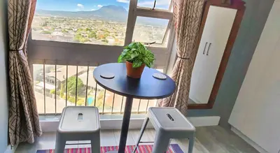 a table and two stools in front of a window at Views Views and more Views Stunning 2 bed Apartment in Strand