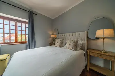 a bedroom with a large white bed and a window at Huguenot Franschhoek in Franschhoek