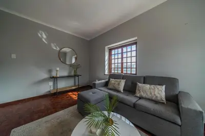 a living room with a gray couch and a mirror at Huguenot Franschhoek in Franschhoek